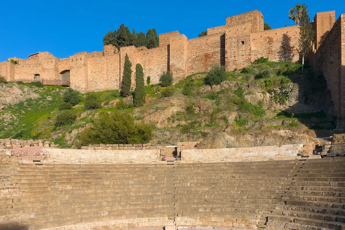 The Roman theatre in Málaga, with its curved stone seating below the brick walls of the Alcazaba on the hillside